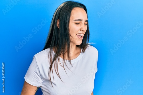 Young hispanic woman wearing casual white t shirt with hand on stomach because nausea, painful disease feeling unwell. ache concept. © Krakenimages.com