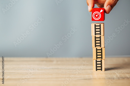 Bullseye is a target of business.Hand putting target board on up arrows which print screen on wooden cube block, business achievement objective target concept. photo