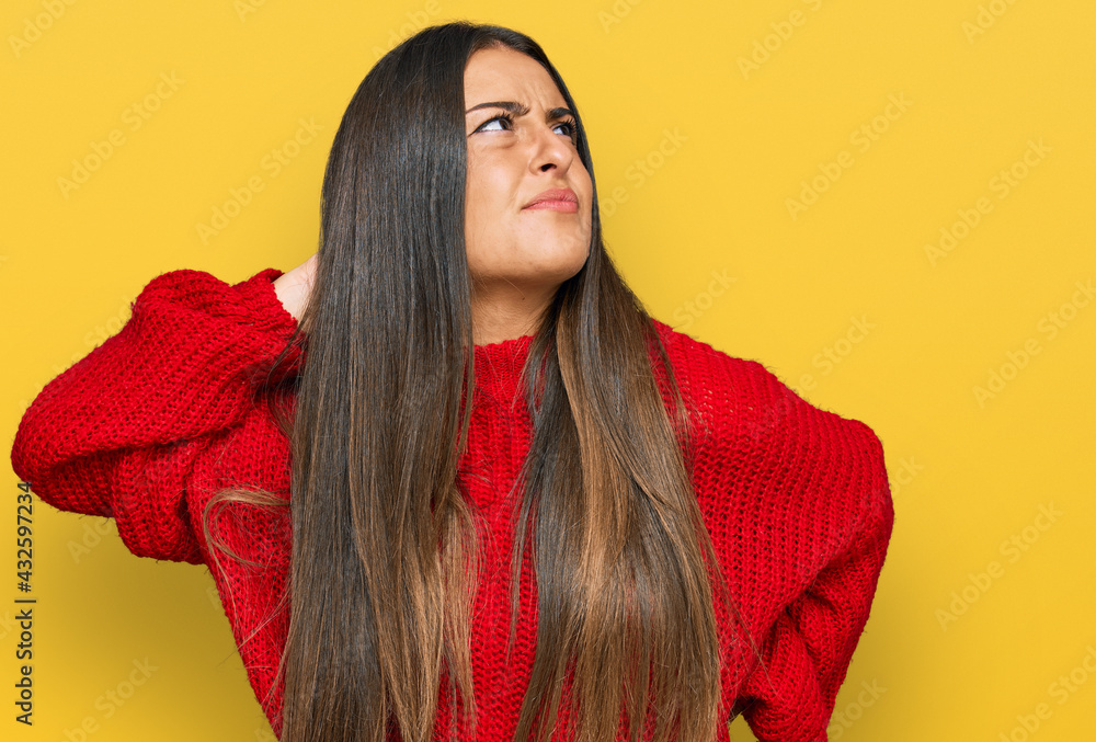 Beautiful hispanic woman wearing casual clothes suffering of neck ache injury, touching neck with hand, muscular pain Beautiful hispanic woman wearing casual clothes suffering of neck ache injury, touching neck with hand, muscular pain