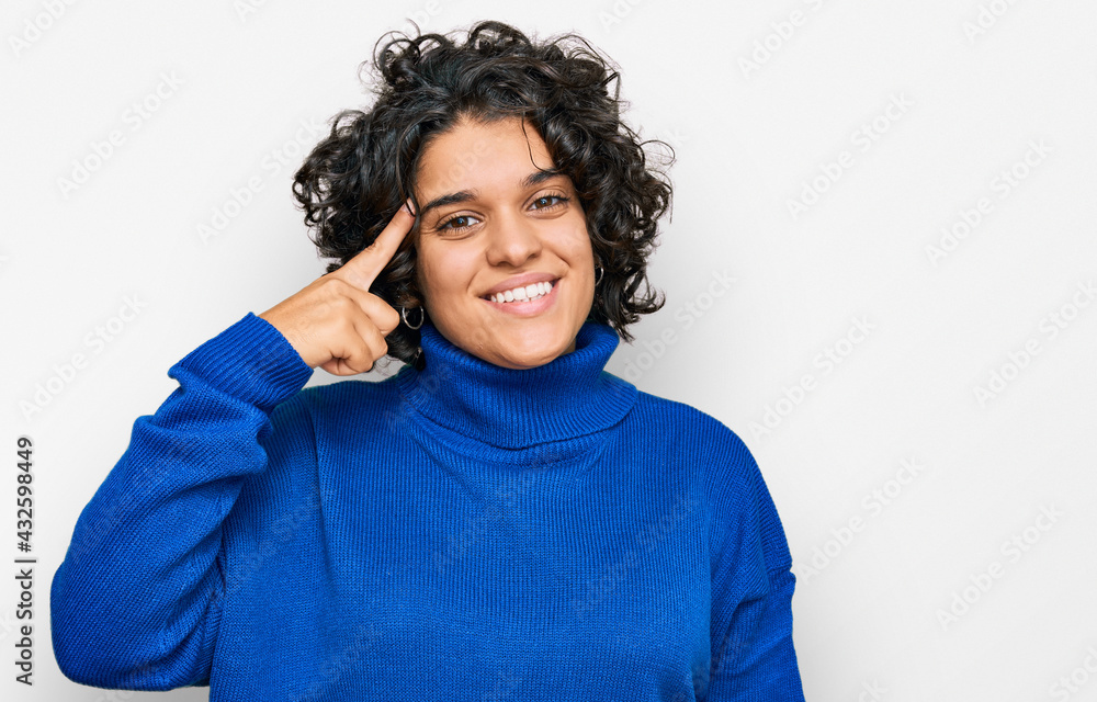 Young hispanic woman with curly hair wearing turtleneck sweater smiling pointing to head with one finger, great idea or thought, good memory Young hispanic woman with curly hair wearing turtleneck sweater smiling pointing to head with one finger, great idea or thought, good memory
