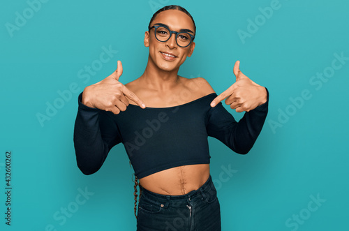 Hispanic transgender man wearing make up and long hair wearing women clothes looking confident with smile on face, pointing oneself with fingers proud and happy.