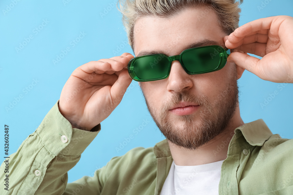 Young man with stylish sunglasses on color background Young man with stylish sunglasses on color background
