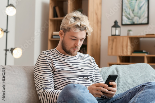 Young man with mobile phone at home