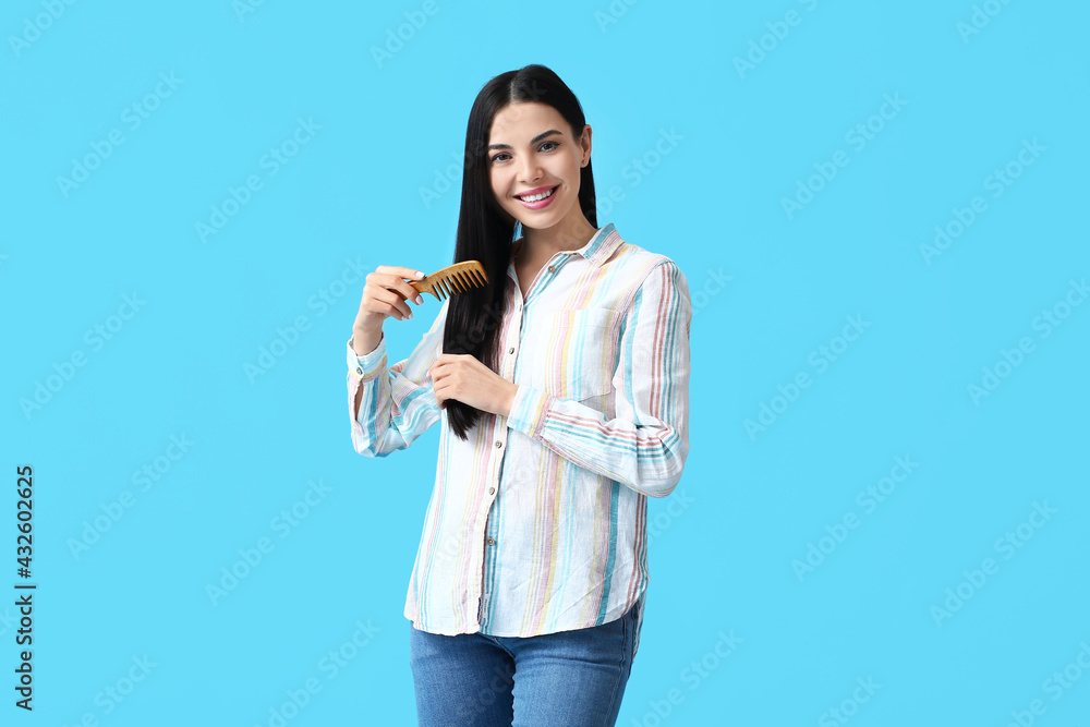 Beautiful young woman with hair comb on color background Beautiful young woman with hair comb on color background