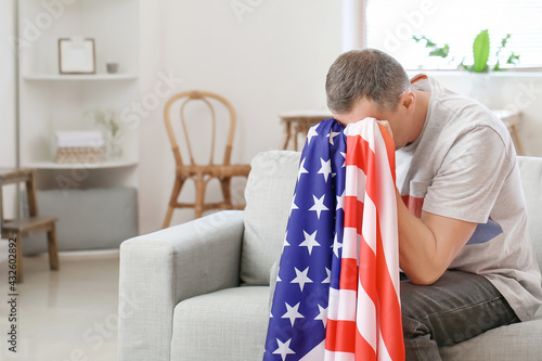 Sad man with USA flag at ho...
