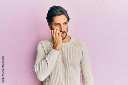 Young hispanic man wearing casual winter sweater looking stressed and nervous with hands on mouth biting nails. anxiety problem.