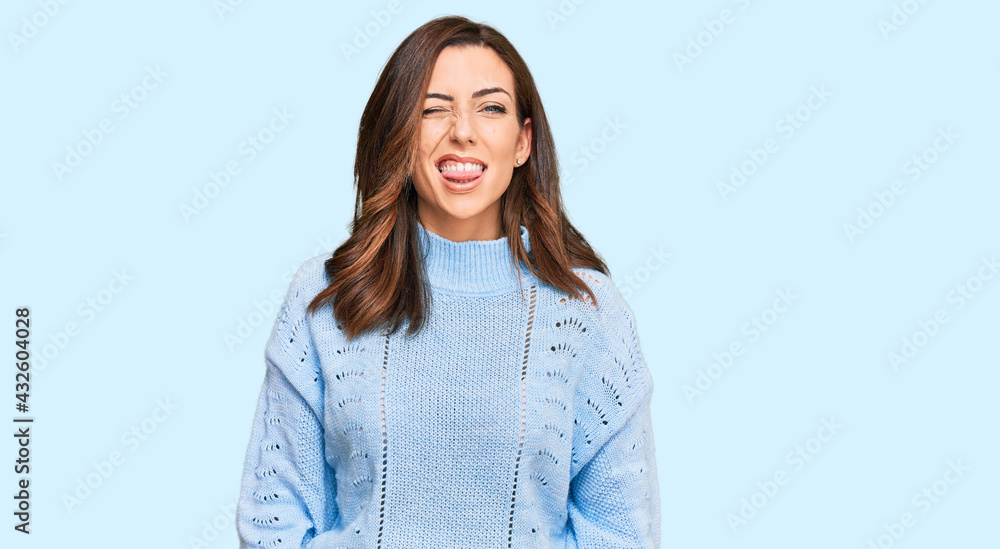 Young brunette woman wearing casual winter sweater sticking tongue out happy with funny expression. emotion concept. Young brunette woman wearing casual winter sweater sticking tongue out happy with funny expression. emotion concept.