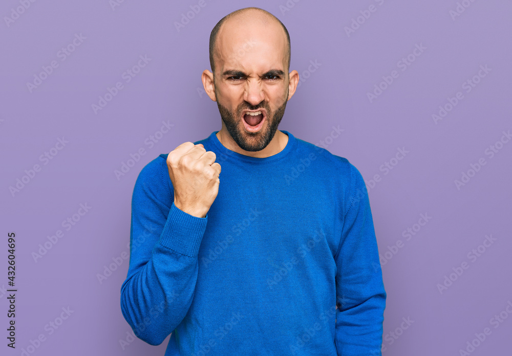 Fototapeta premium Young hispanic man wearing casual clothes angry and mad raising fist frustrated and furious while shouting with anger. rage and aggressive concept.