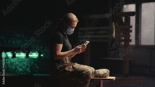 Military woman in mask using smartphone