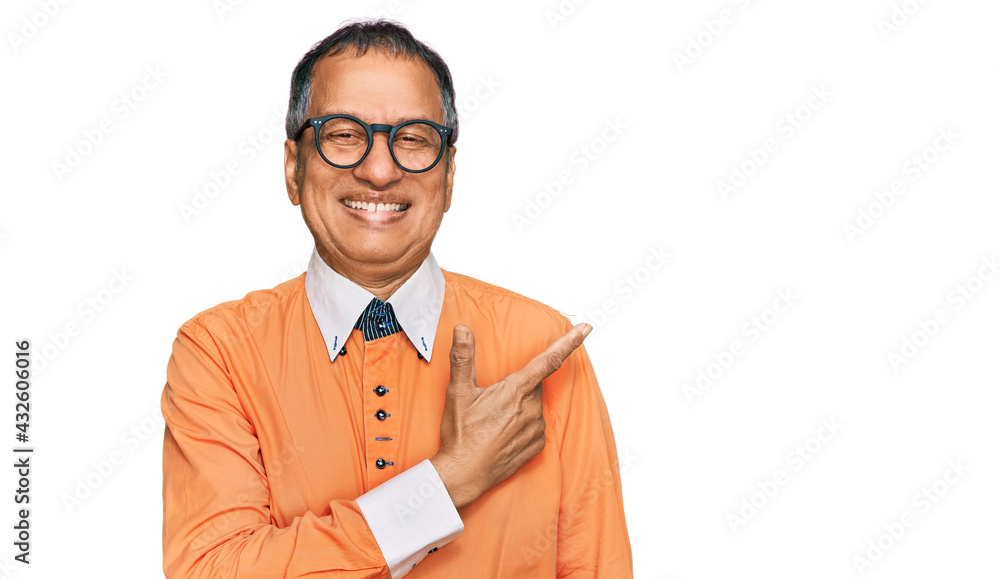 Middle age indian man wearing casual clothes and glasses cheerful with a smile of face pointing with hand and finger up to the side with happy and natural expression on face Middle age indian man wearing casual clothes and glasses cheerful with a smile of face pointing with hand and finger up to the side with happy and natural expression on face
