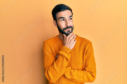 Young hispanic man wearing casual clothes with hand on chin thinking about question, pensive expression. smiling with thoughtful face. doubt concept.