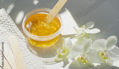 Sugar paste or wax honey in a transparent jar on a white background. Sugaring. Depilation and beauty concept. Waxing.