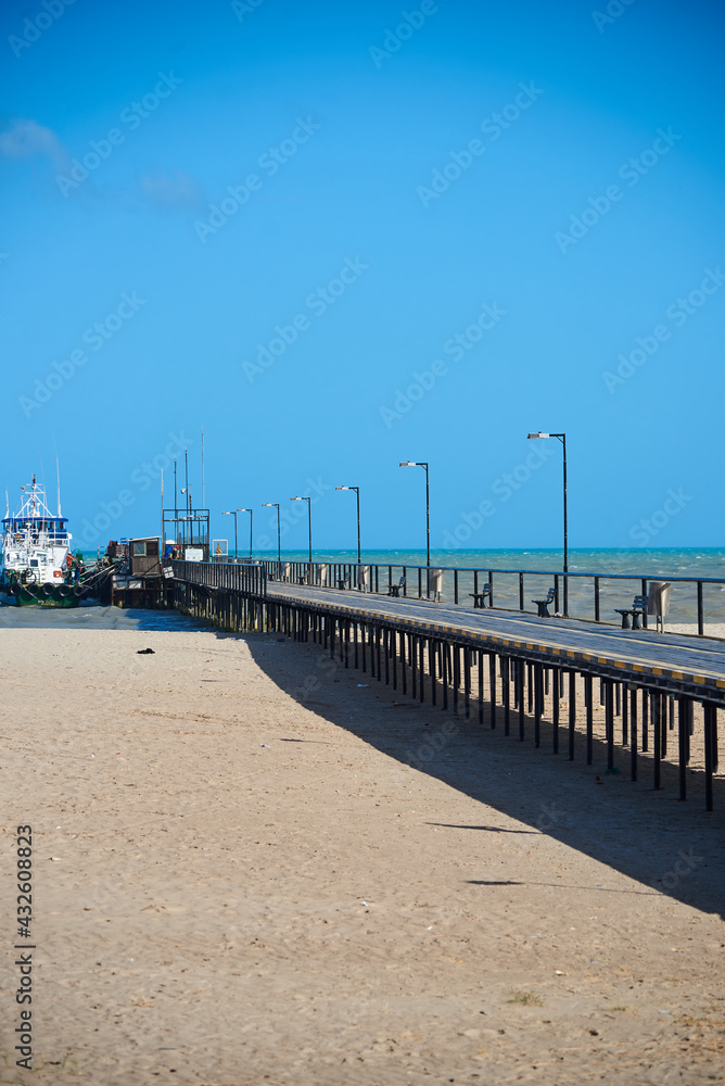 Wooden pier on a sandy beach that leads to a jetty in the city of Riohacha. Colombia.