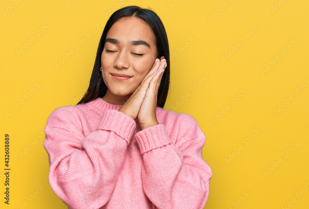 Young asian woman wearing casual winter sweater sleeping tired dreaming and posing with hands together while smiling with closed eyes. Young asian woman wearing casual winter sweater sleeping tired dreaming and posing with hands together while smiling with closed eyes.