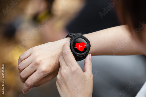 Fotografie Digital wristwatch with heart icons, female checking measuring heart rate in smartwatch