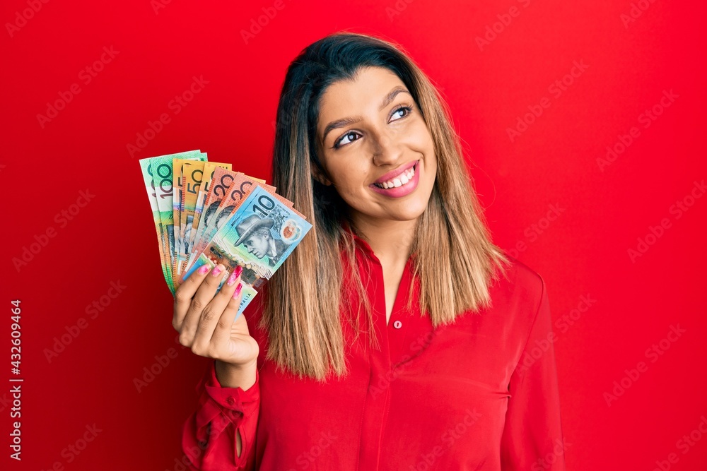 Beautiful brunette woman holding australian dollars smiling looking to the side and staring away thinking. Beautiful brunette woman holding australian dollars smiling looking to the side and staring away thinking.