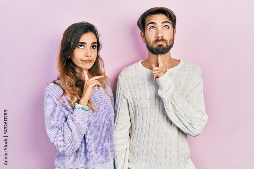 Young hispanic couple wearing casual clothes thinking concentrated about doubt with finger on chin and looking up wondering Young hispanic couple wearing casual clothes thinking concentrated about doubt with finger on chin and looking up wondering