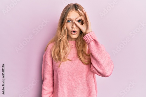 Beautiful young caucasian girl wearing casual clothes doing ok gesture shocked with surprised face, eye looking through fingers. unbelieving expression.