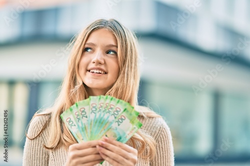 Beautiful caucasian teenager smiling happy holding russian 200 ruble banknotes at the city. photo