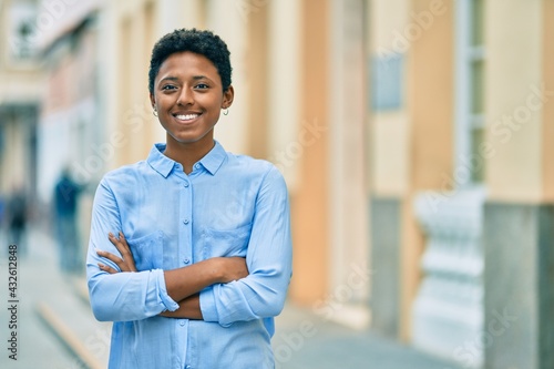 Young african american girl with crossed arms smiling happy at the city.