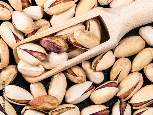 wooden scoop on heap of pistachio seeds closeup