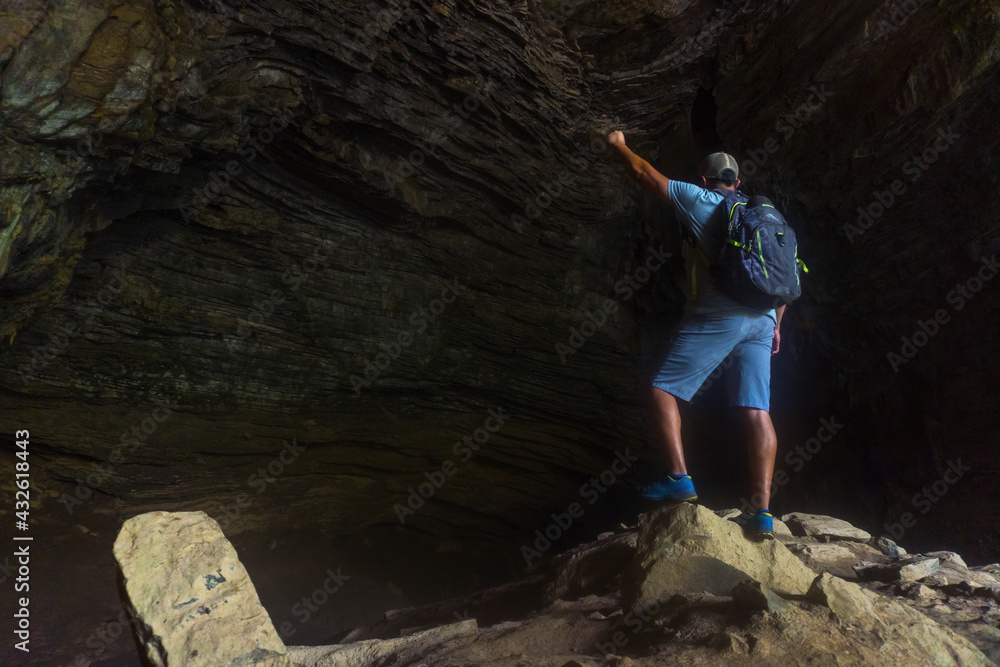 A Hispanic hiker raising his arms while standing on rocks in the Gruta de Totomachapa cave, Mexico
