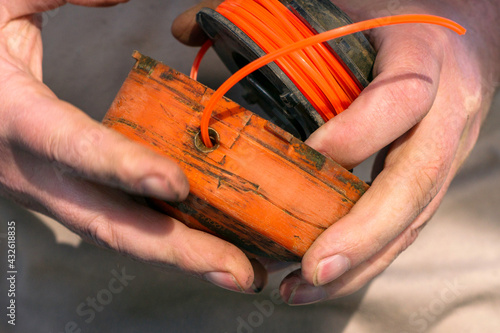 a man collects a grass trimmer reel after replacing the fishing line in it