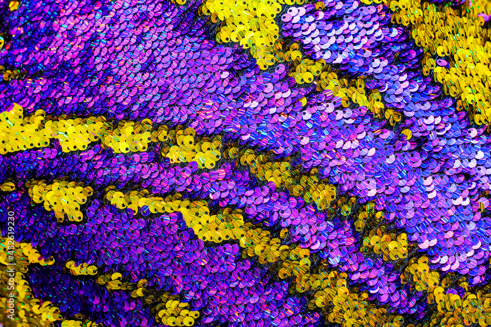 The shiny bright texture of the sequins changes color. Purple and yellow. Fabric for fancy dresses