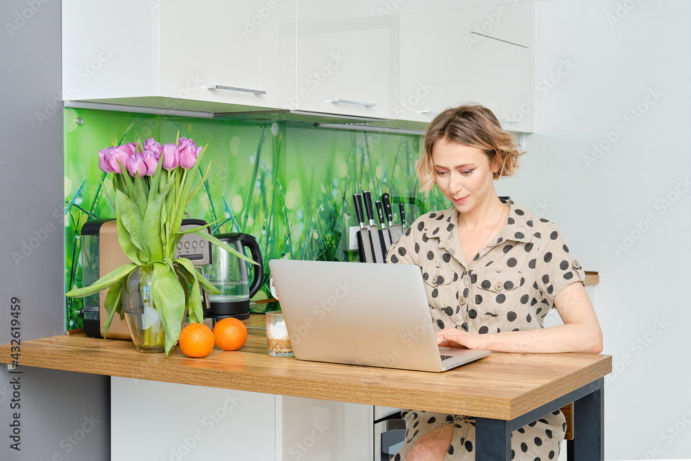 Woman working at home office, she is sitting in the kitchen with her laptop Woman working at home office, she is sitting in the kitchen with her laptop