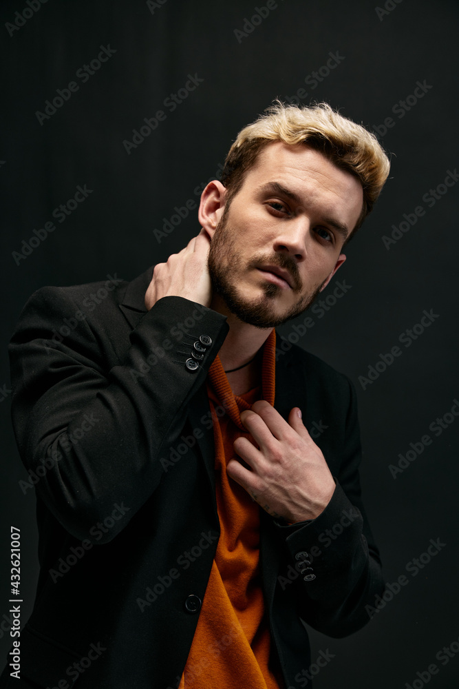 man in orange sweater and jacket on a dark background gesturing with his hands close-up cropped view