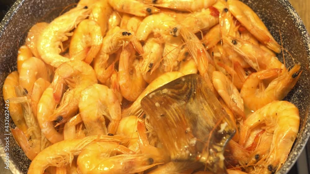 The shrimp are fried in a large skillet in the kitchen. Flavored seafood steamed when cooking The shrimp are fried in a large skillet in the kitchen. Flavored seafood steamed when cooking