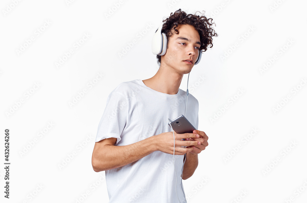 curly-haired guy in headphones with a phone in his hands music technology curly-haired guy in headphones with a phone in his hands music technology