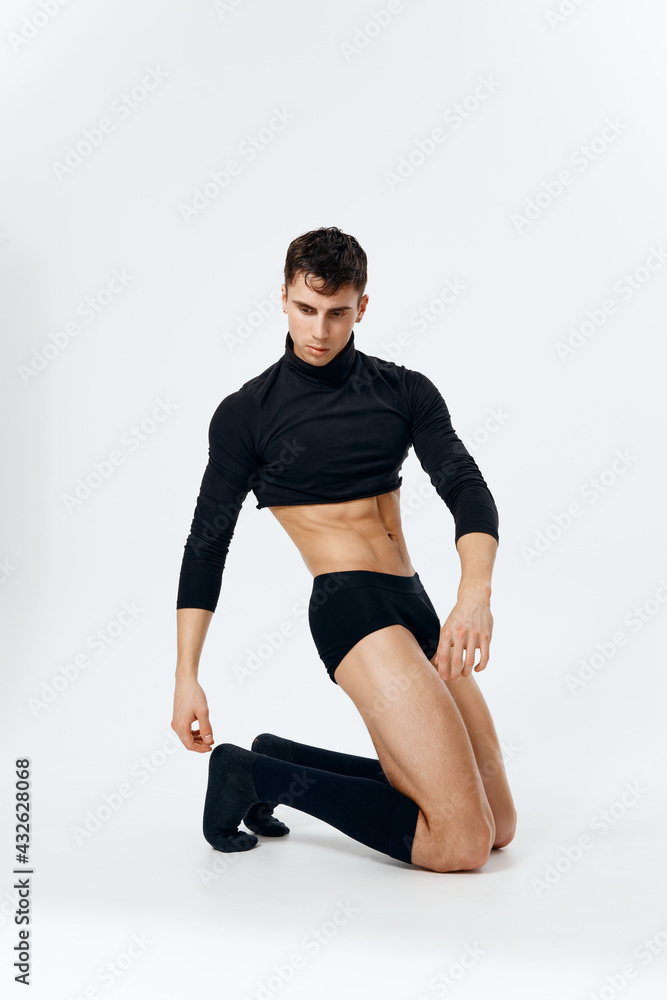 a man in shorts, socks and a sweater kneels on a light background side view a man in shorts, socks and a sweater kneels on a light background side view