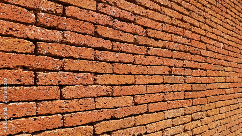 Side view of red-brown stone wall. Background or laterite brick wall texture in your design. Selective focus