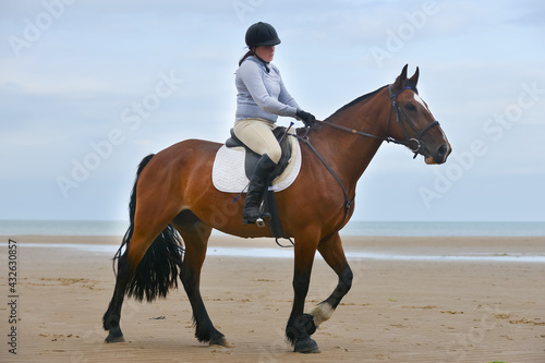 Fototapeta Naklejka Na Ścianę i Meble -  Young woman and her horse enjoy the excitement of riding on the beach in wales UK  
