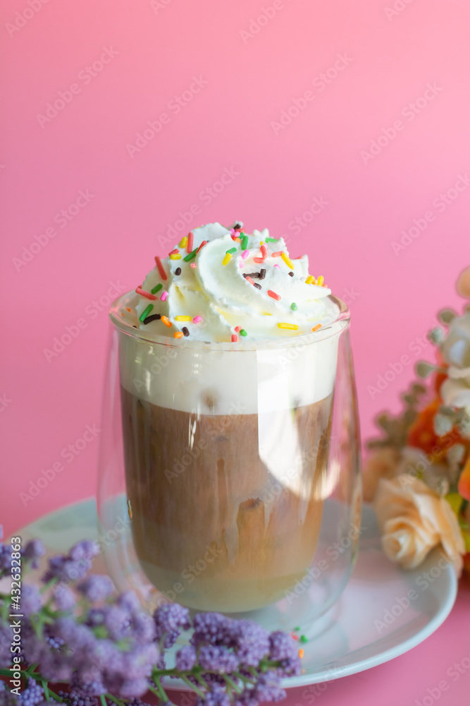 Ice coffee with a layer of milk and whipping cream with color sugar topping on pink background. Beverage and drink at the party concept. Ice coffee with a layer of milk and whipping cream with color sugar topping on pink background. Beverage and drink at the party concept.