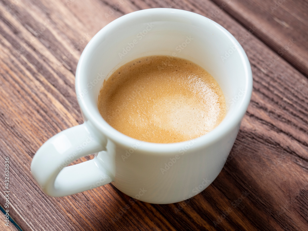 a white cup with a delicious and aromatic espresso on a wooden background. side view a white cup with a delicious and aromatic espresso on a wooden background. side view