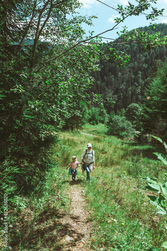mother with little toddler daughter hiking by mountain forest