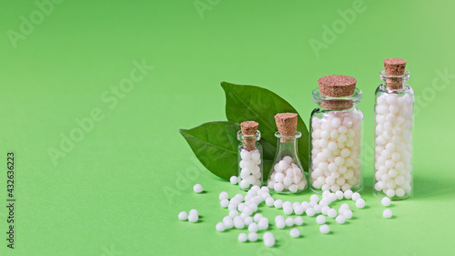 Bottles with homeopathic globules on a green background. Homeopathic medicine.