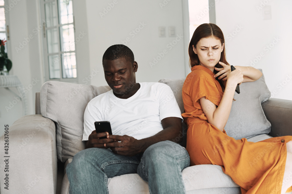 man and woman at home on the couch with phones in their hands communication conflict man and woman at home on the couch with phones in their hands communication conflict