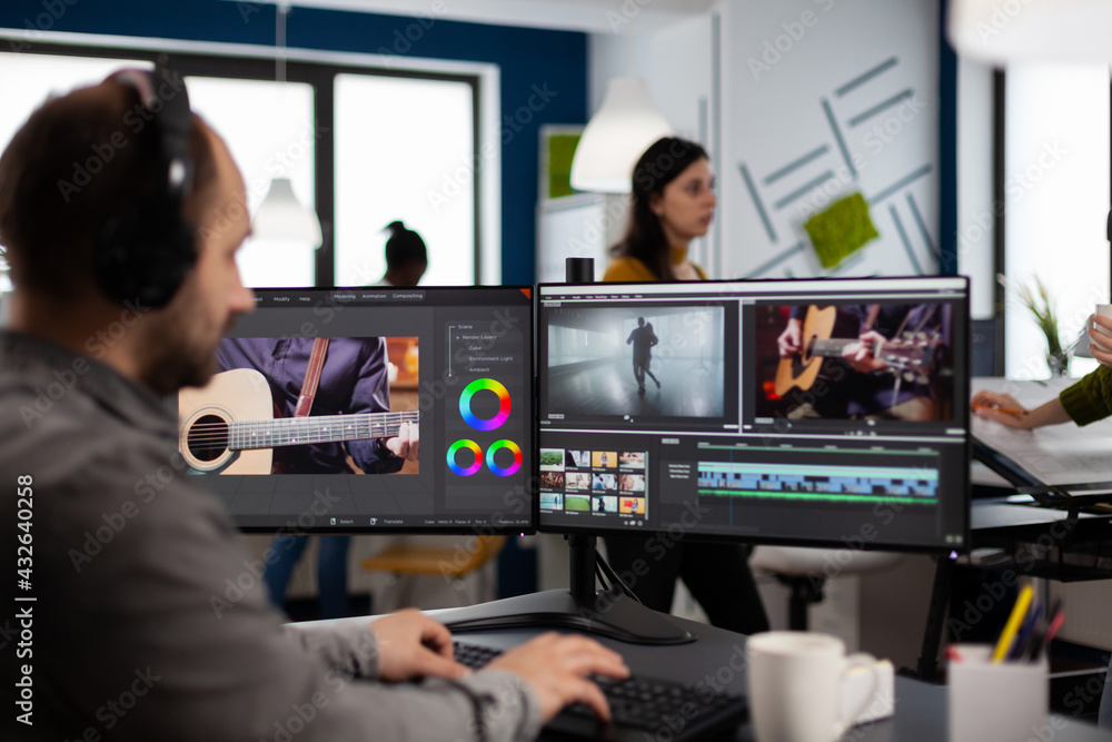 Video maker listening music at headphones editing movie using post