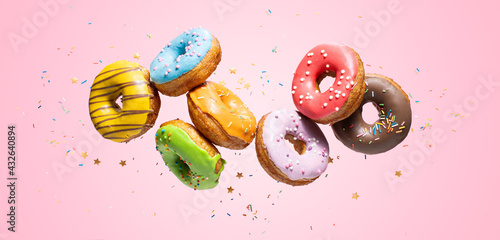 Εκτύπωση καμβά Colorful decorated donuts falling in motion on pink background with sprinkling