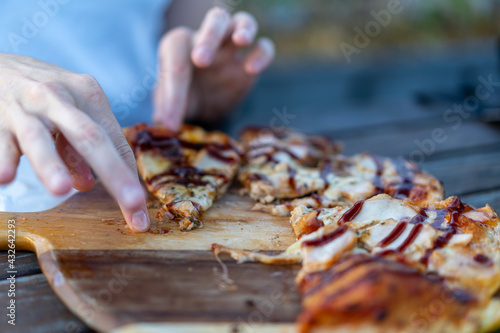person eating a pizza with bbq sauce at an outdoor cafe