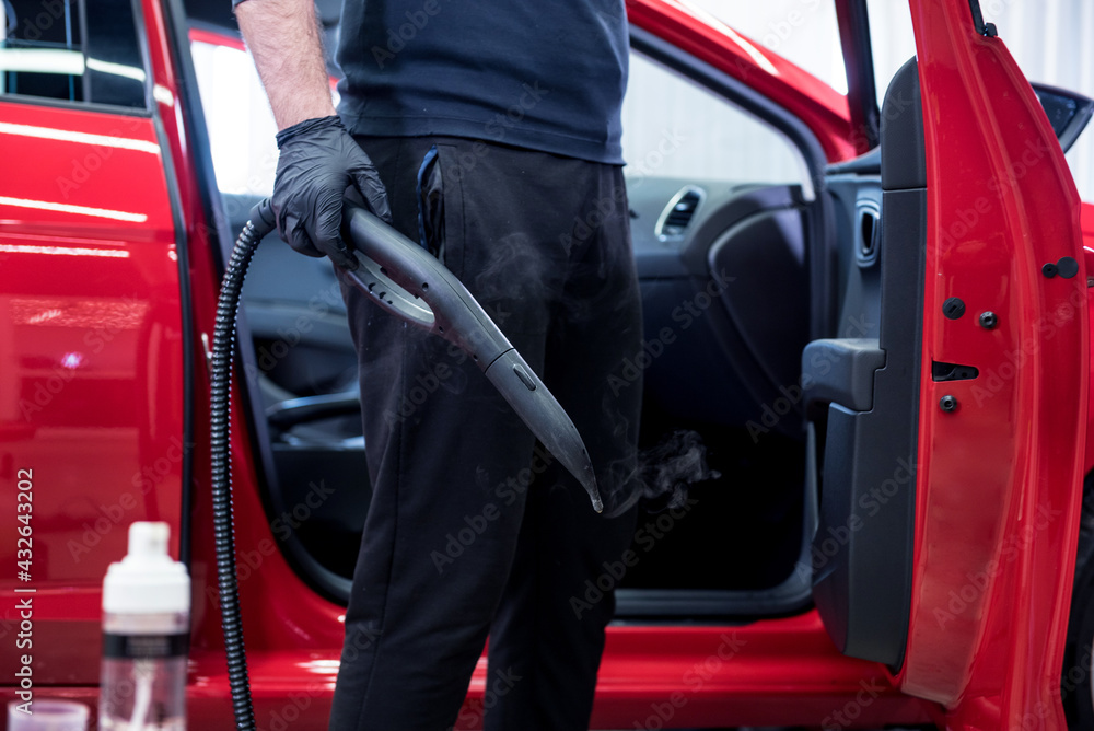 Car service worker cleans interiror with steam cleaner Car service worker cleans interiror with steam cleaner