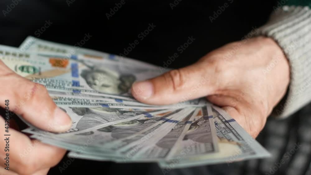 Close-up of male hands holding a fan of American dollar bills. A man is counting money, holding banknotes in his hands. American money in the hands of a man. selective focus, shallow depth of field Close-up of male hands holding a fan of American dollar bills. A man is counting money, holding banknotes in his hands. American money in the hands of a man. selective focus, shallow depth of field