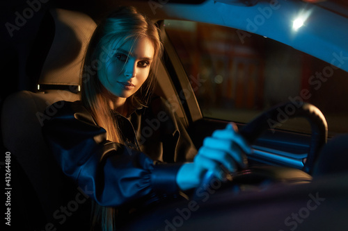 Beautiful young woman driving car at night