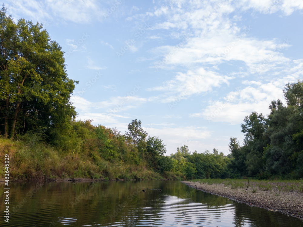 Sunny day with clouds in nature, Landscape with river and forested riparian zone during summer. Sunny day with clouds in nature, Landscape with river and forested riparian zone during summer.