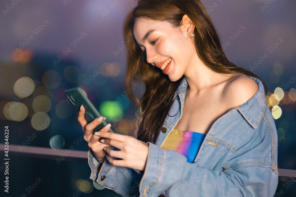 Obraz premium Portrait of smiling pretty young woman using phone on rooftop city bangkok.Female using mobile phone make vlog and live in social media .