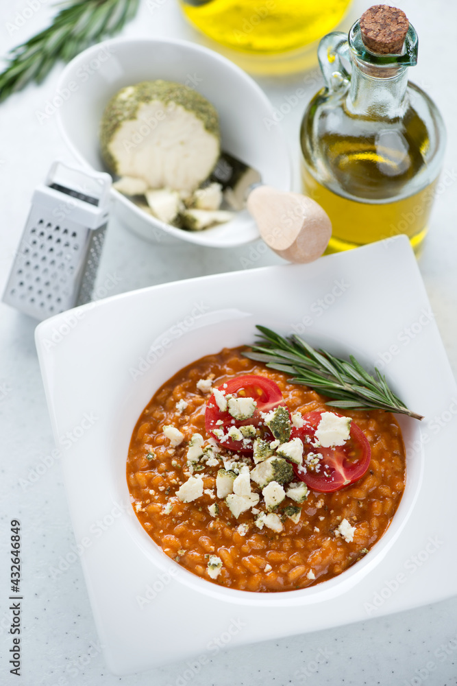 Risotto with sun dried tomato pesto and belper knolle, elevated view on a white stone background, vertical shot Risotto with sun dried tomato pesto and belper knolle, elevated view on a white stone background, vertical shot