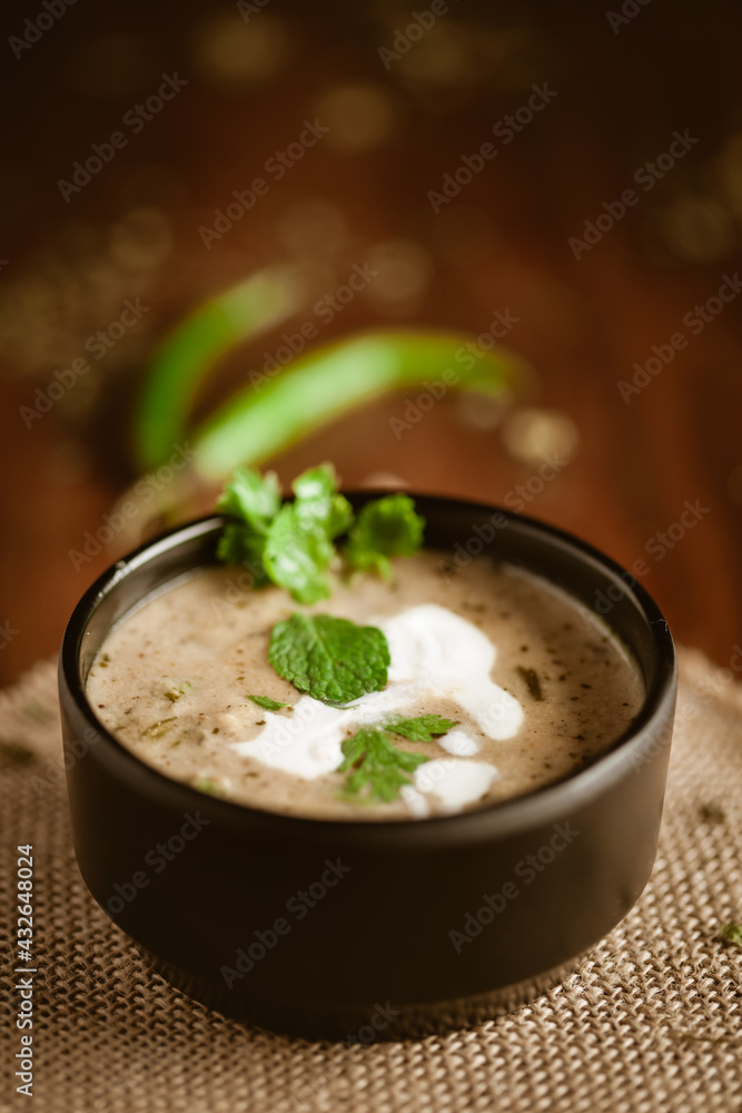 Close-up of Methi-Matar-Malai with white curry with fresh green chilies, mint leaves, and onions. A popular, delicious Indian recipe in a black bowl over wooden background. Close-up of Methi-Matar-Malai with white curry with fresh green chilies, mint leaves, and onions. A popular, delicious Indian recipe in a black bowl over wooden background.